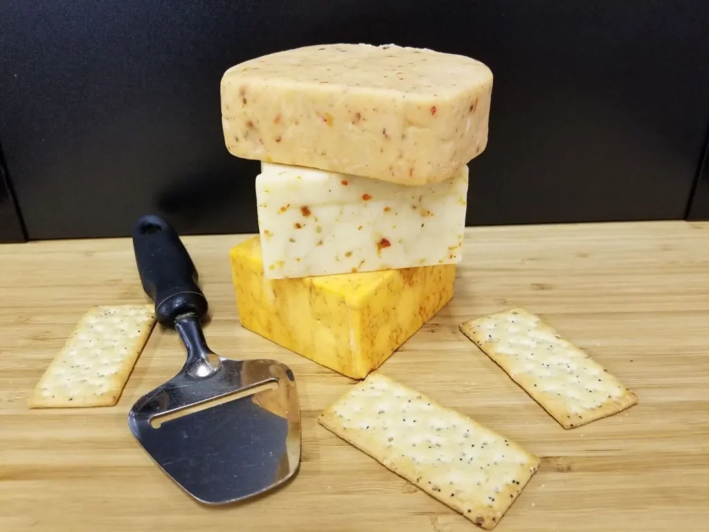 Picture of fresh cut cheese with crackers and a cheese cutter